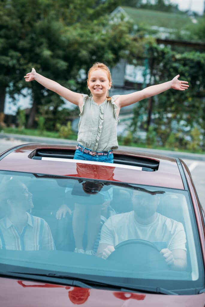 adorable little girl peering out of car sun roof